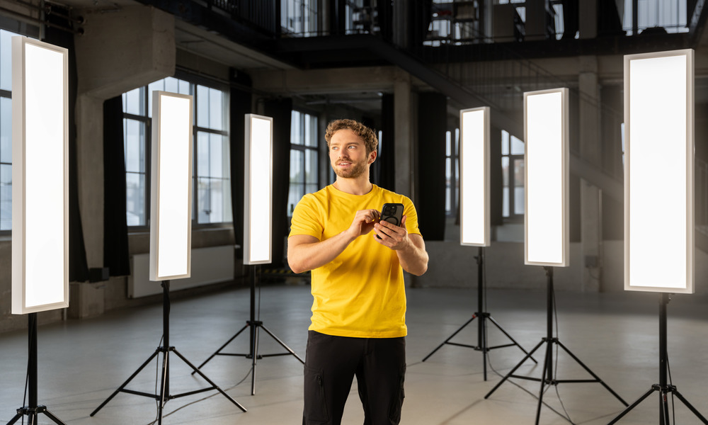 feel free.twnty3 trilux twenty3 Mann steht mit Mobiltelefon und bedient smart stehleuchten